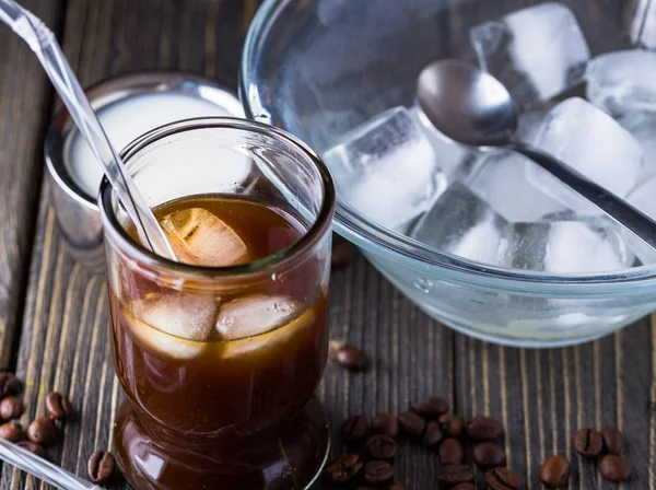 Karanlık doğal masa üzerinde küçük bir bardak buzlu kahve.