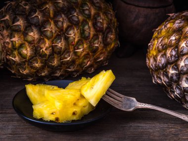 Bıçak ve arkasında bütün ananas ile eski rustik masada Dilimlenmiş ananas. Siyah arka plan.