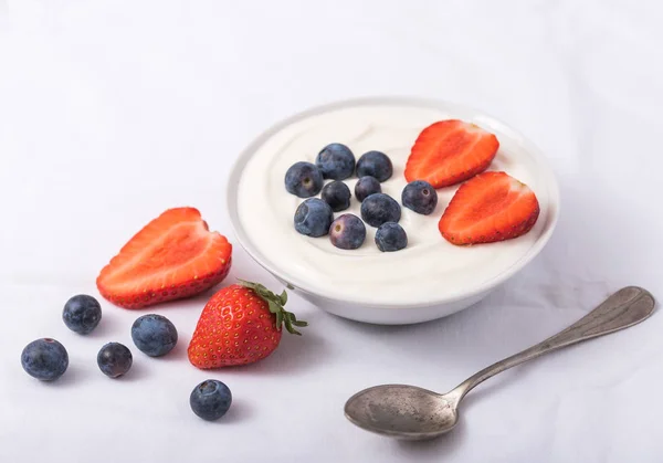 Joghurt fehér tálban eper és áfonya fehér alapon. — Stock Fotó