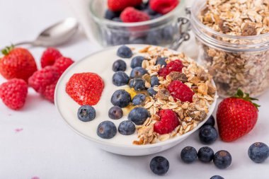 Beyaz kasede yoğurt, beyaz arka planda çilek ve yaban mersini. Beyaz kasede yoğurt, beyaz arka planda çilek ve yaban mersini..