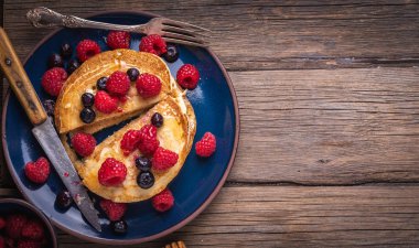 Böğürtlenli krep ve ahşap masada mavi tabakta ahududu..