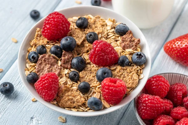 Mısır gevreği, yaban mersini ve ahududu ile beyaz masada sağlıklı bir kahvaltı..