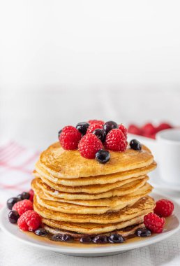 Beyaz tabakta ahududu ve yaban mersinli ev yapımı krep..