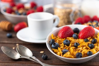 Mısır gevreği, yaban mersini ve beyaz fincanlı çilekli sağlıklı kahvaltı..