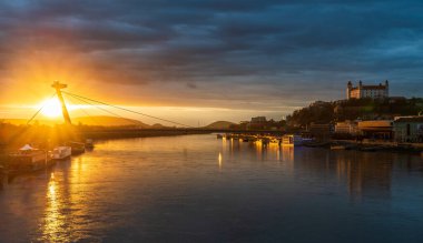 Bratislava Kalesi ve Köprü Restoranı, bulutlu hava altında gün batımında.