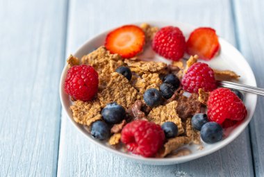 Böğürtlenli granola ve beyaz kaseli ahududu koyu beyaz masa.