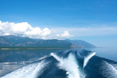 dağ arka plan ile Baykal Gölü üzerinde bir tekne dalgaları