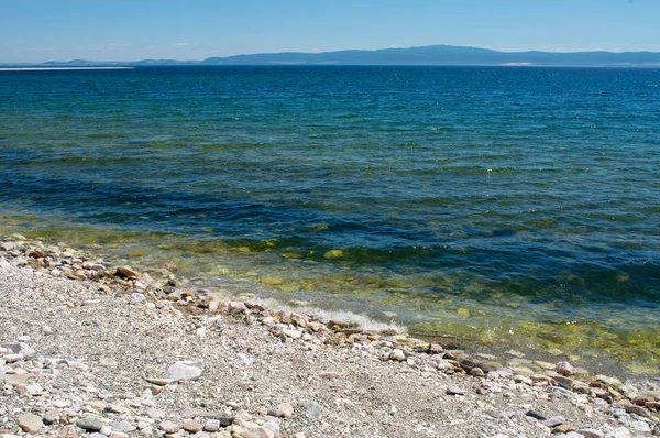 Steinigen Ufer des Baikalsees blauer Himmel Hintergrund — Stockfoto