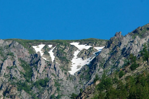 Montañas nevadas en verano con puesta de sol y cielo azul —  Fotos de Stock
