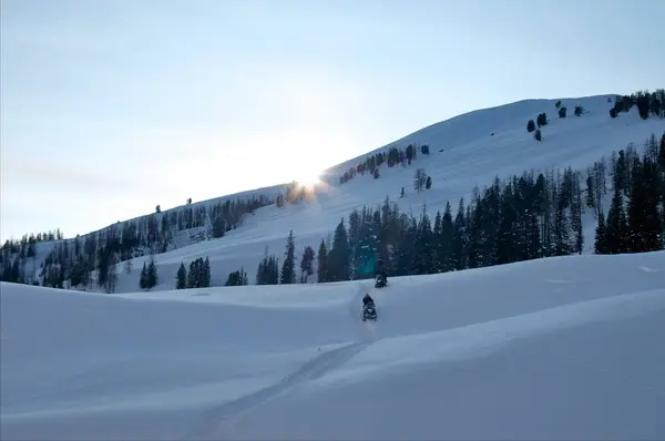 Dois homens em um snowmobile de fundo de montanhas — Fotografia de Stock