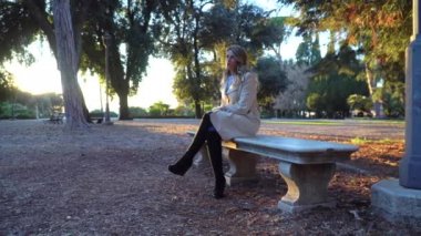 Gün batımında sonbahar Park taş bankta oturan kadın