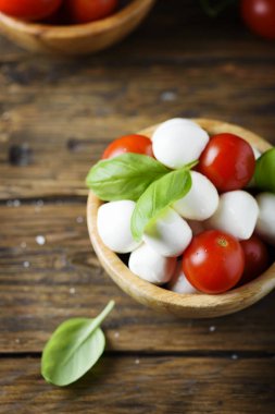 Mozzarella peyniri, domates ve fesleğen yaprakları ahşap kase hizmet ile İtalyan meze closeup görünümü