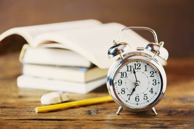 Çalar saat, kitap, defter, kalem ve silgi ahşap tablo