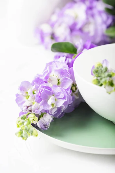 Lilac spring flowers laying on plate near cup