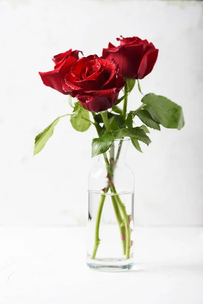 Tender red roses in transparent glass vase