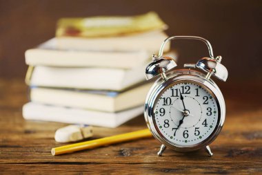 çalar saat ve ahşap masa üzerine kitaplar