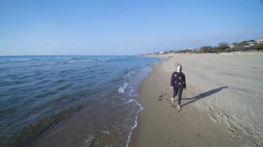 Genç bir kadın kumsalda yürüyor