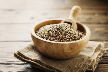 Çiğ kırmızı, beyaz ve siyah quinoa karışımı ahşap kase kepçe ile hizmet.