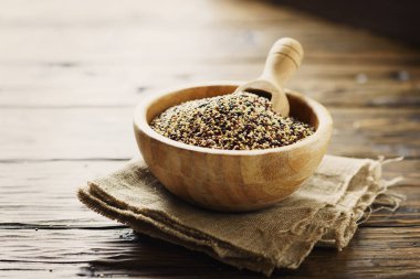 Çiğ kırmızı, beyaz ve siyah quinoa karışımı ahşap kase kepçe ile hizmet.