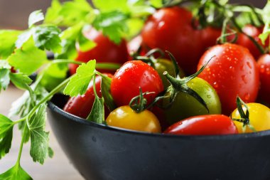 Siyah taş kase maydanoz ile kırmızı, sarı ve yeşil domates karışımı