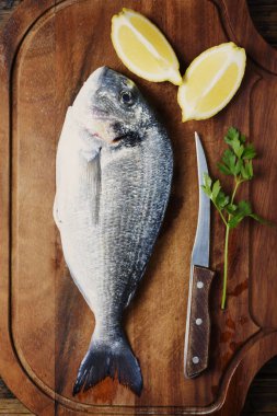 Taze çiğ balık üstten görünüm ahşap tahta üzerinde limon dilimleri ile servis