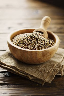 Çiğ kırmızı, beyaz ve siyah quinoa karışımı ahşap kase kepçe ile hizmet.