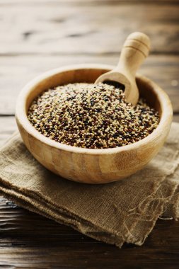 Çiğ kırmızı, beyaz ve siyah quinoa karışımı ahşap kase kepçe ile hizmet.