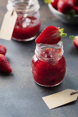 Sweet homemade strawberry jam on the rustic black background