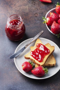 Toasts with strawberry jam for breakfast, rustic style and selective focus image