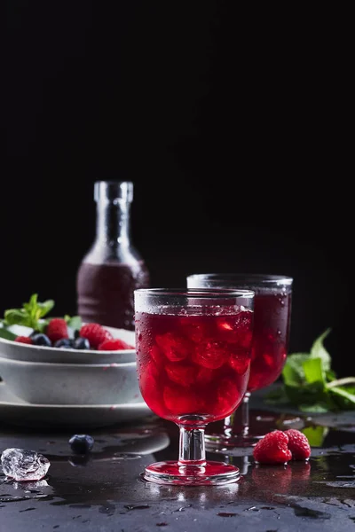 Glasses of a red berry juice on the black table, selective focus
