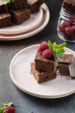 Siyah arkaplanda ahududu ve nane aromalı çikolatalı pasta parçaları, seçici odaklı resim.