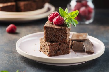 Siyah arkaplanda ahududu ve nane aromalı çikolatalı pasta parçaları, seçici odaklı resim.