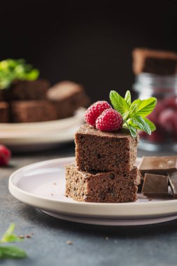 Siyah arkaplanda ahududu ve nane aromalı çikolatalı pasta parçaları, seçici odaklı resim.