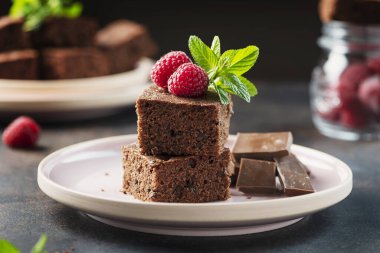 Siyah arkaplanda ahududu ve nane aromalı çikolatalı pasta parçaları, seçici odaklı resim.