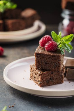 Siyah arkaplanda ahududu ve nane aromalı çikolatalı pasta parçaları, seçici odaklı resim.