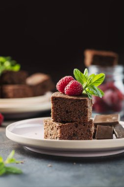 Siyah arkaplanda ahududu ve nane aromalı çikolatalı pasta parçaları, seçici odaklı resim.