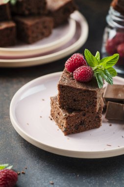 Siyah arkaplanda ahududu ve nane aromalı çikolatalı pasta parçaları, seçici odaklı resim.