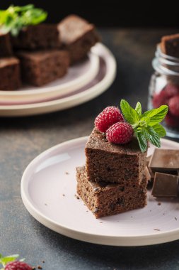 Siyah arkaplanda ahududu ve nane aromalı çikolatalı pasta parçaları, seçici odaklı resim.