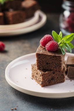Siyah arkaplanda ahududu ve nane aromalı çikolatalı pasta parçaları, seçici odaklı resim.