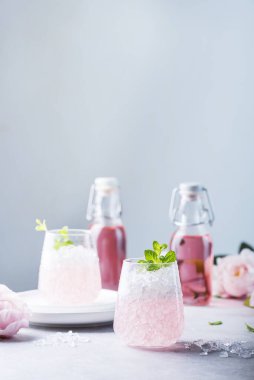 Ezilmiş buzlu pembe kokteyl ve açık arkaplanda nane, seçici odak görüntüsü