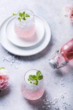 Ezilmiş buzlu pembe kokteyl ve açık arkaplanda nane, seçici odak görüntüsü