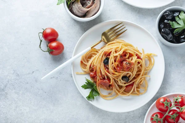 トマトと伝統的なイタリアのパスタ オリーブ ケッパー アンチョビとパセリ トップビューの画像 — ストック写真