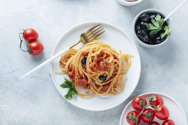 Traditional italian pasta with tomato, olives, capers, anchovies and parsley, top view image clipart