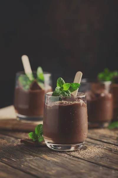 Sweet mousse with chocolate and mint on the rustic table, selective focus and toned image