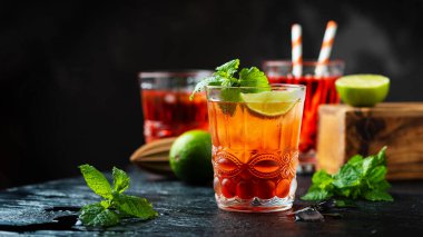 Siyah masada buzlu ve limonlu taze kırmızı kokteyl, seçici odaklanma ve kaydırma biçimi