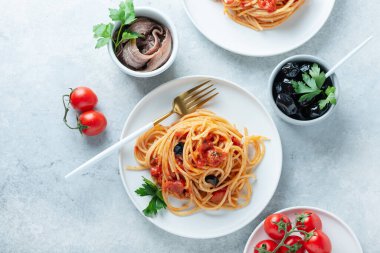 Traditional italian pasta with tomato, olives, capers, anchovies and parsley, top view image clipart