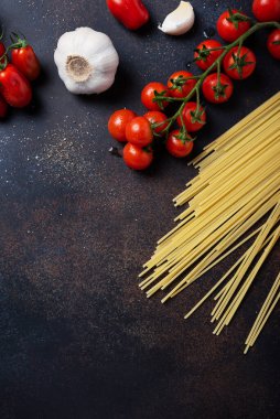 İtalyan makarnası pişirmek için gerekenler: spagetti, domates ve siyah masada sarımsak. Fotokopi alanı olan en üst görüntü