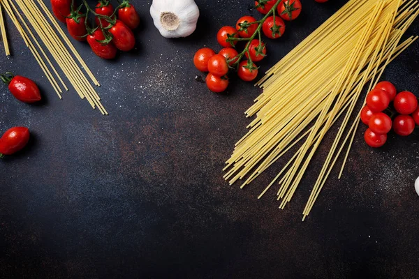 İtalyan makarnası pişirmek için gerekenler: spagetti, domates ve siyah masada sarımsak. Fotokopi alanı olan en üst görüntü
