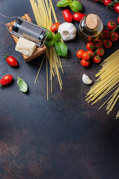 İtalyan yemeği kavramı: spagetti, domates, fesleğen, sarımsak, peynir ve siyah masadaki zeytinyağı. Kopyalama alanı olan üst görünüm