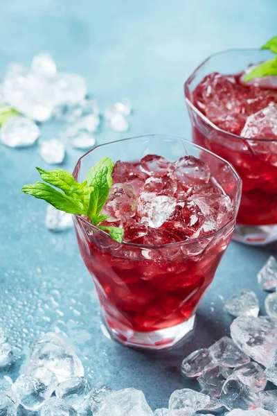 Red summer cocktail with ice and mint, selective focus image